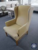 A 20th century wing back armchair in mustard colour fabric