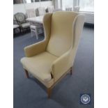 A 20th century wing back armchair in mustard colour fabric