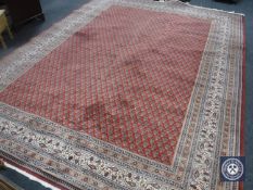 A machine made fringed carpet on red ground