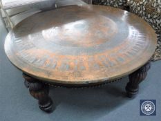 A large circular copper topped coffee table depicting Egyptian figures