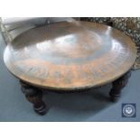 A large circular copper topped coffee table depicting Egyptian figures