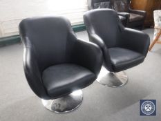 A pair of black leather swivel armchairs on chrome bases