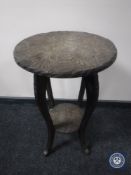 A heavily carved two tier occasional table