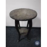 A heavily carved two tier occasional table