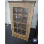A 20th century stripped pine glazed door wall cabinet