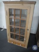 A 20th century stripped pine glazed door wall cabinet