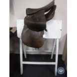Two leather saddles and wooden stand