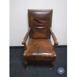 An antique mahogany framed armchair upholstered in brown leather