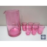 An antique ruby glass jug together with six small glasses
