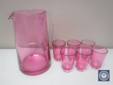 An antique ruby glass jug together with six small glasses