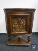 An oak corner cabinet with a carved panel door