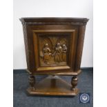 An oak corner cabinet with a carved panel door