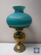 An early 20th century brass oil lamp with chimney and green glass shade