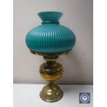 An early 20th century brass oil lamp with chimney and green glass shade