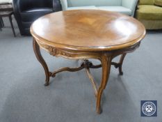 A circular walnut coffee table on cabriole legs