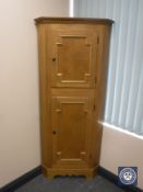 A blond oak double door corner cabinet