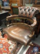 A brown leather revolving captain's style armchair,