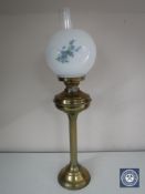 A brass oil lamp with glass shade and chimney