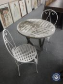 A garden table together with two metal chairs
