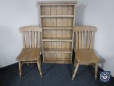 A pair of pine kitchen chairs together with a stripped pine bookshelf