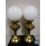 A pair of antique brass oil lamps with glass shades