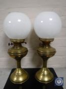A pair of antique brass oil lamps with glass shades