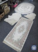 Two fringed Indian rugs on cream ground together with two sheep skin rugs