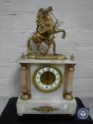 A gilt metal and alabaster mantel clock with enamel dial surmounted by a figure of a man with a