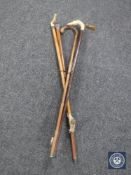 Five antique walking sticks together with a bag containing walking stick badges