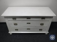 A continental oak painted three drawer chest on bun feet