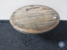 A whisky barrel lid coffee table on metal hairpin legs bearing White Horse advertisement