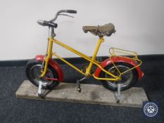 A vintage child's bike mounted on a pine board