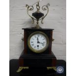 A Victorian marble and slate mantel clock on brass feet surmounted by an urn,