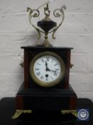 A Victorian marble and slate mantel clock on brass feet surmounted by an urn,