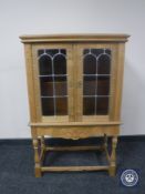 A blond oak double door cabinet with stained glass leaded doors fitted a drawer beneath