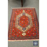A Caucasian design rug on red ground,