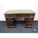 A mahogany twin pedestal writing desk fitted nine drawers with inset green tooled leather panel