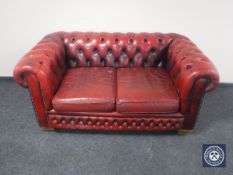 A red Chesterfield style buttoned leather two seater settee