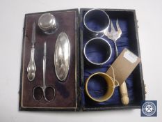 A cased silver four piece nail kit, a silver pronged fork, two silver napkin rings,