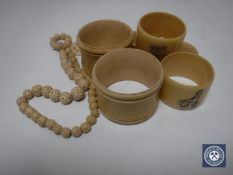 Five antique ivory napkin rings together with a beaded necklace