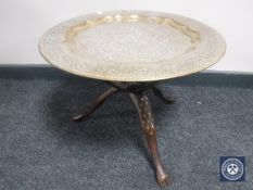 An Eastern brass topped table on three-way folding hardwood and brass base