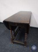 An antique oak gateleg table fitted a drawer on turned legs