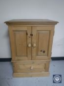 A stripped pine double door cabinet fitted a drawer