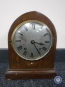 An inlaid mahogany cased Empire mantel clock on brass feet with silvered dial