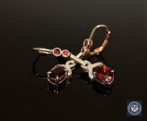A pair of silver and rose gold plated garnet drop earrings, with two oval-cut garnets weighing 3.