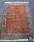 A Bokhara design rug on terracotta ground,