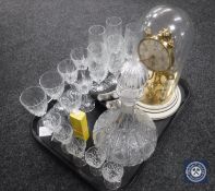 An anniversary clock under shade, decanter, drinking glasses,