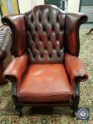 A Chesterfield style oxblood buttoned leather wingback armchair,