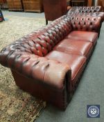 A Chesterfield style oxblood buttoned leather three seater settee,