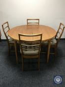 A 1970's circular teak extending dining table and four ladder back chairs